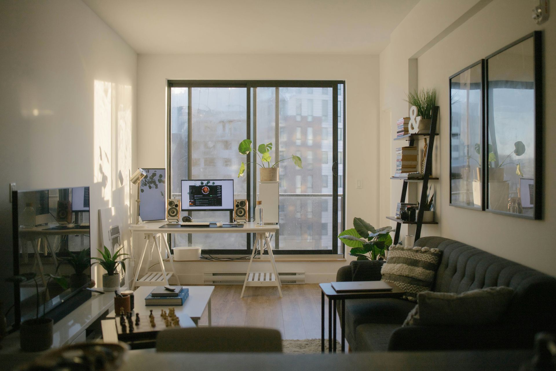 A sunlit home office with a desk, computer, and sofa in a living room